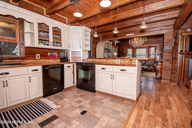 kitchen featuring black appliances, beam ceiling, hanging light fixtures, and wooden walls