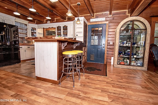 bar featuring butcher block countertops, black fridge, white cabinets, and light hardwood / wood-style flooring