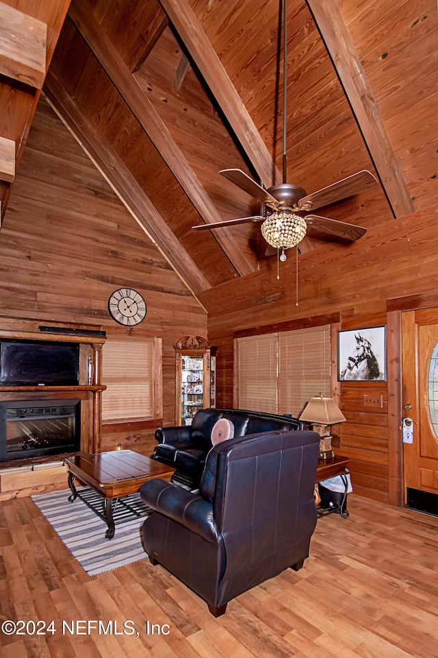 living room featuring wood-type flooring, high vaulted ceiling, beam ceiling, and wood walls