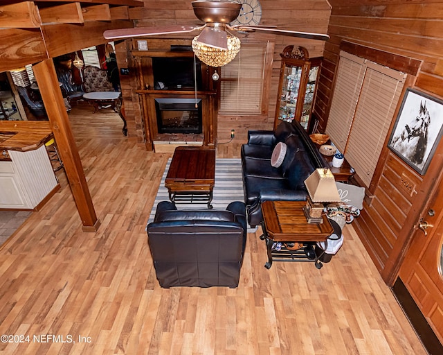 living room with light hardwood / wood-style floors, ceiling fan, and wood walls