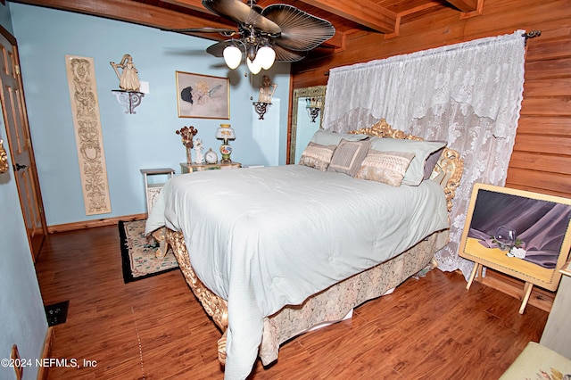 bedroom with ceiling fan, hardwood / wood-style floors, beamed ceiling, and wood walls