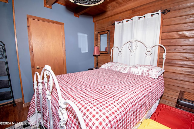 bedroom featuring wood ceiling, wooden walls, hardwood / wood-style flooring, beamed ceiling, and a closet