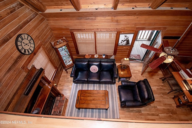 living room with wood walls, wood-type flooring, and beam ceiling