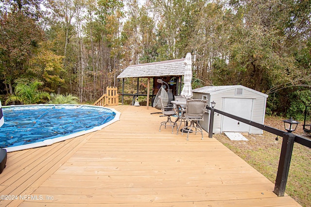 wooden terrace with a covered pool and a storage shed