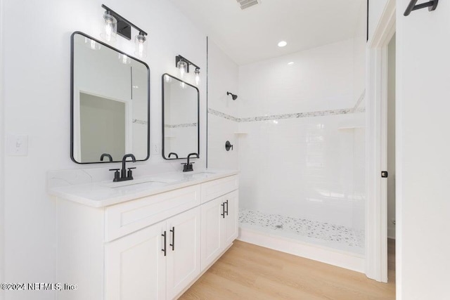 bathroom featuring tiled shower, hardwood / wood-style floors, and vanity