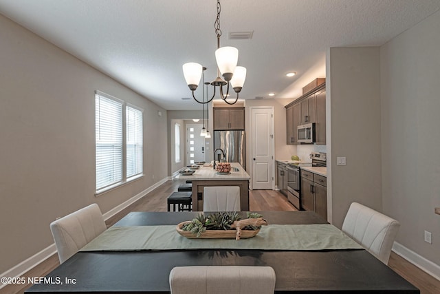 dining space with sink, a chandelier, and light wood-type flooring