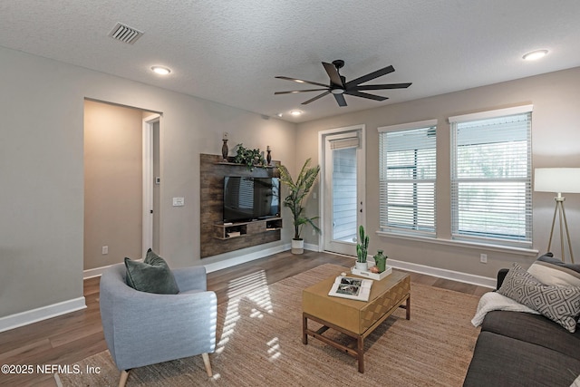 living room featuring hardwood / wood-style floors, a textured ceiling, and ceiling fan