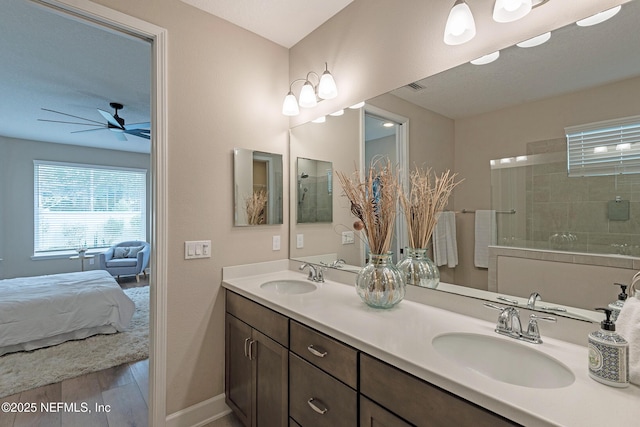 bathroom with a tile shower, vanity, and wood-type flooring