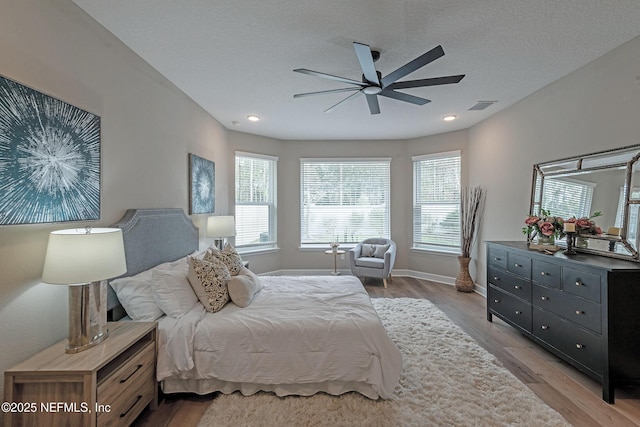 bedroom featuring ceiling fan, light hardwood / wood-style flooring, and a textured ceiling