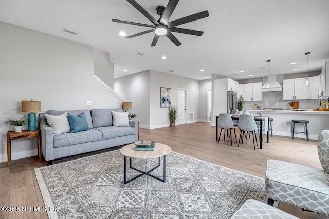 living room with light hardwood / wood-style flooring and ceiling fan