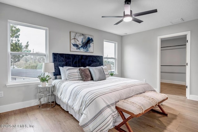 bedroom with multiple windows, hardwood / wood-style floors, and ceiling fan