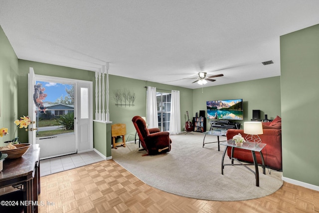 living room with ceiling fan, a healthy amount of sunlight, and a textured ceiling