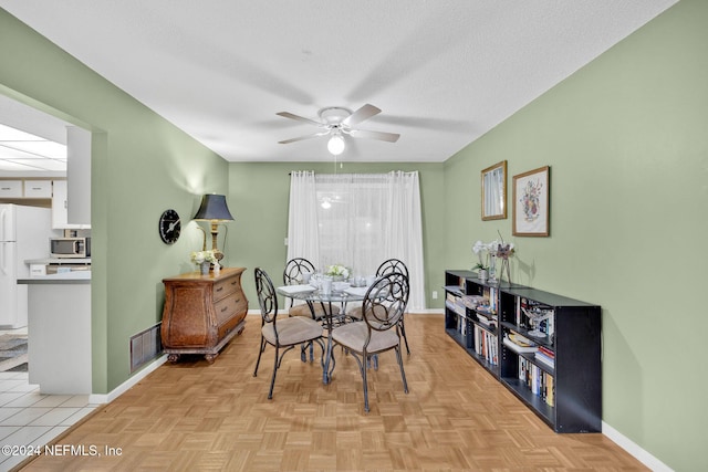 dining area with ceiling fan, light parquet floors, and a textured ceiling