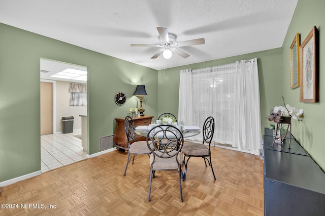 dining space featuring a textured ceiling, light parquet flooring, and ceiling fan