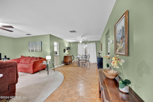 living room featuring ceiling fan, light parquet flooring, and a textured ceiling