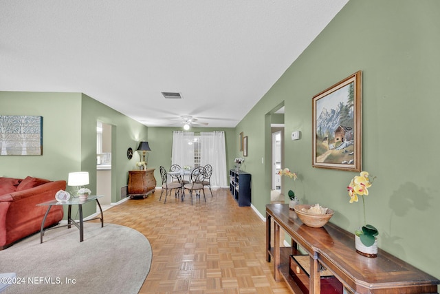 living room featuring a textured ceiling, light parquet flooring, and ceiling fan