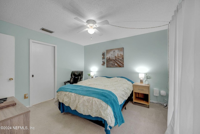 bedroom featuring ceiling fan, light carpet, and a textured ceiling