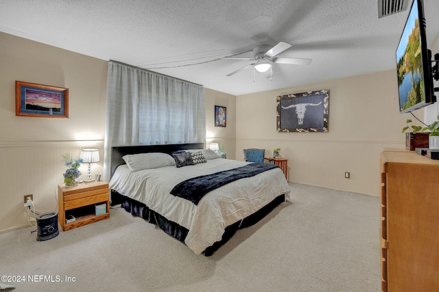 carpeted bedroom featuring ceiling fan and a textured ceiling