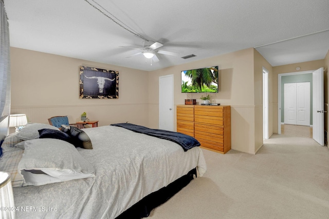 carpeted bedroom with ceiling fan and a textured ceiling