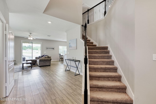 staircase with wood-type flooring and ceiling fan