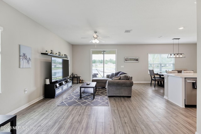 living room with light hardwood / wood-style floors, ceiling fan, and a healthy amount of sunlight