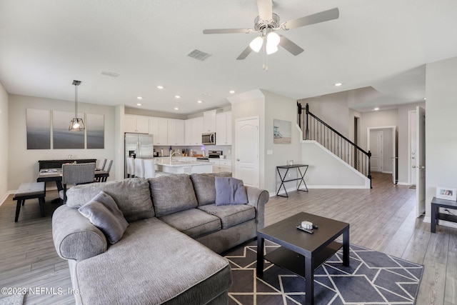 living room featuring wood-type flooring, ceiling fan, and sink