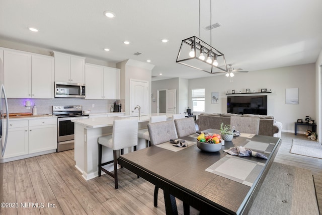 dining room with ceiling fan and light wood-type flooring