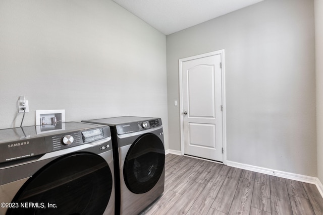 laundry area with washing machine and dryer and light hardwood / wood-style floors