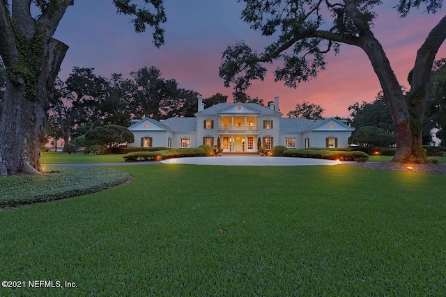 view of front of home with a lawn and a balcony