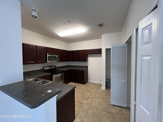 kitchen featuring kitchen peninsula, sink, a textured ceiling, and appliances with stainless steel finishes