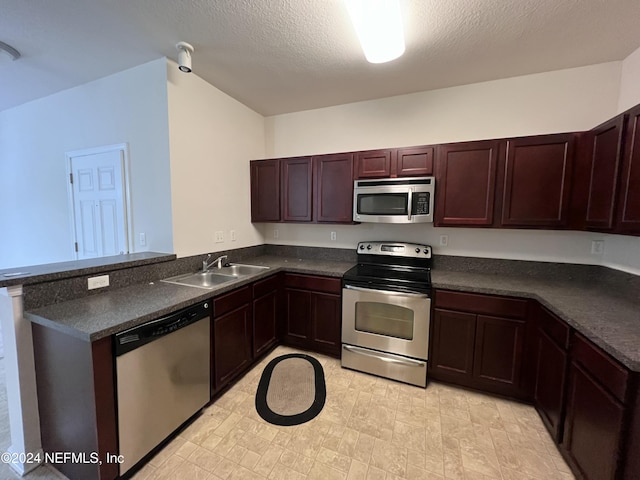 kitchen with a textured ceiling, kitchen peninsula, sink, and appliances with stainless steel finishes