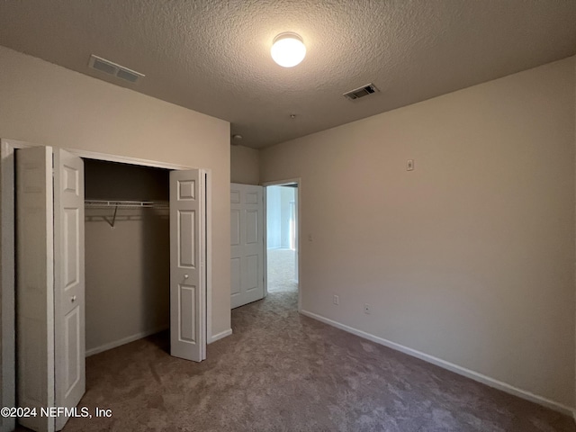 unfurnished bedroom with carpet, a textured ceiling, and a closet