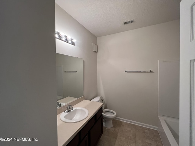 bathroom featuring a textured ceiling, vanity, and toilet