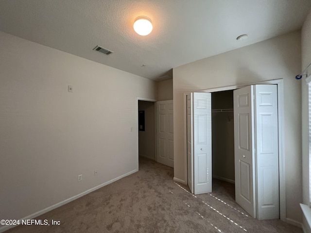 unfurnished bedroom with carpet flooring, a closet, and a textured ceiling