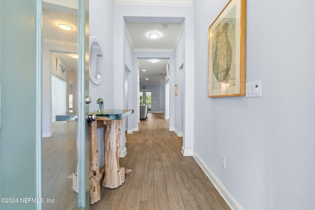 hallway with hardwood / wood-style flooring and ornamental molding