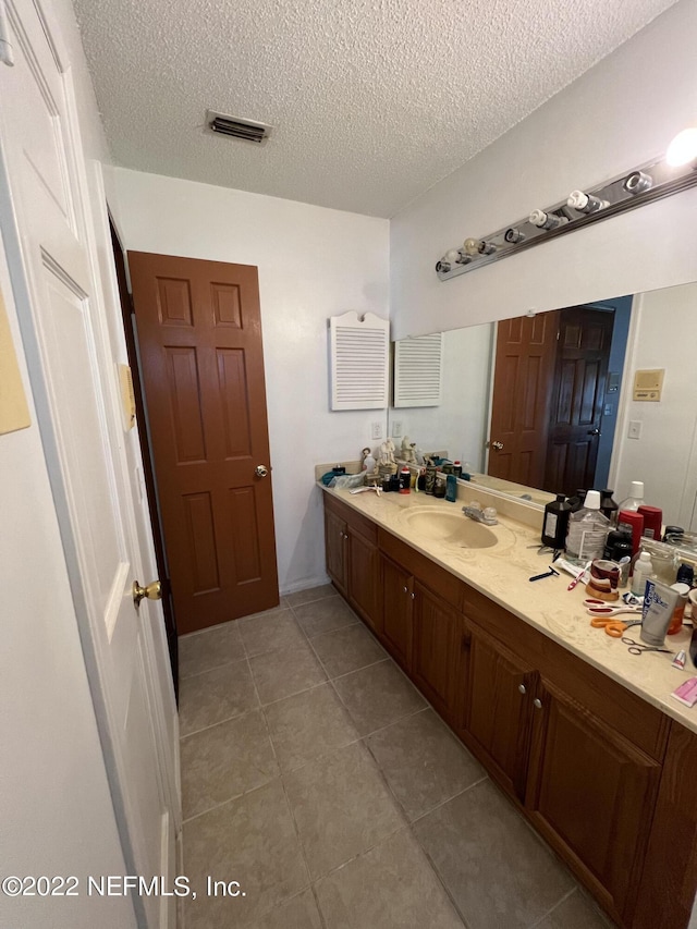 bathroom with tile patterned floors, vanity, and a textured ceiling