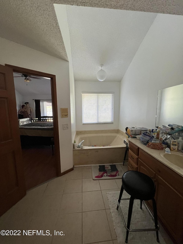 bathroom with vanity, tile patterned floors, ceiling fan, a textured ceiling, and a tub