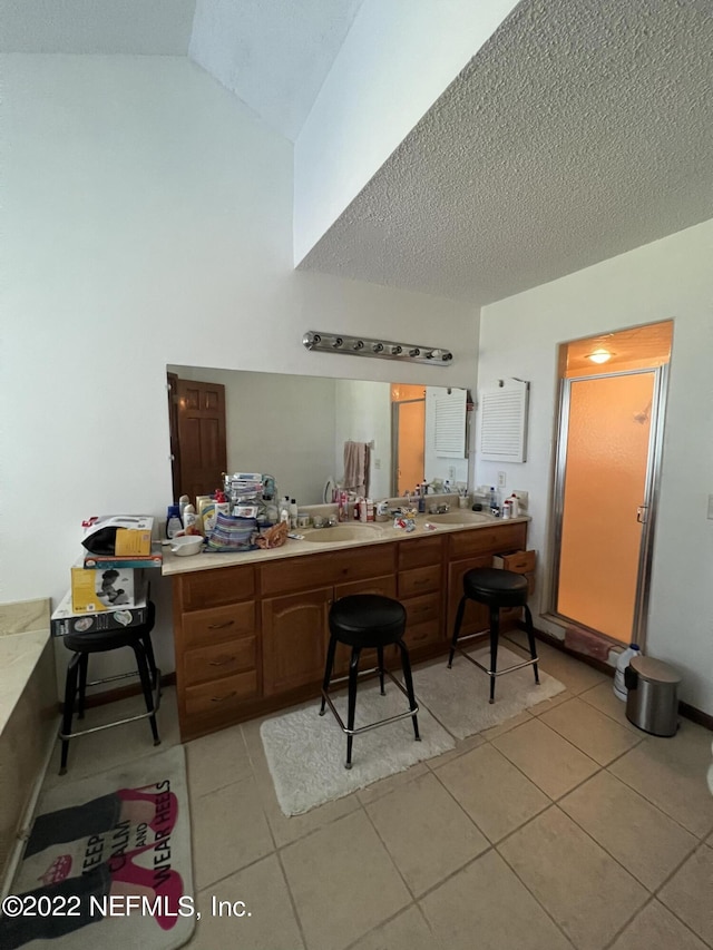 kitchen featuring sink, light tile patterned floors, a textured ceiling, and vaulted ceiling