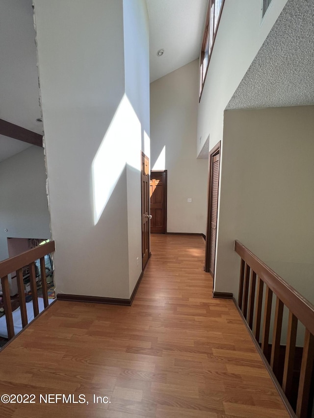 hallway featuring light hardwood / wood-style floors and high vaulted ceiling