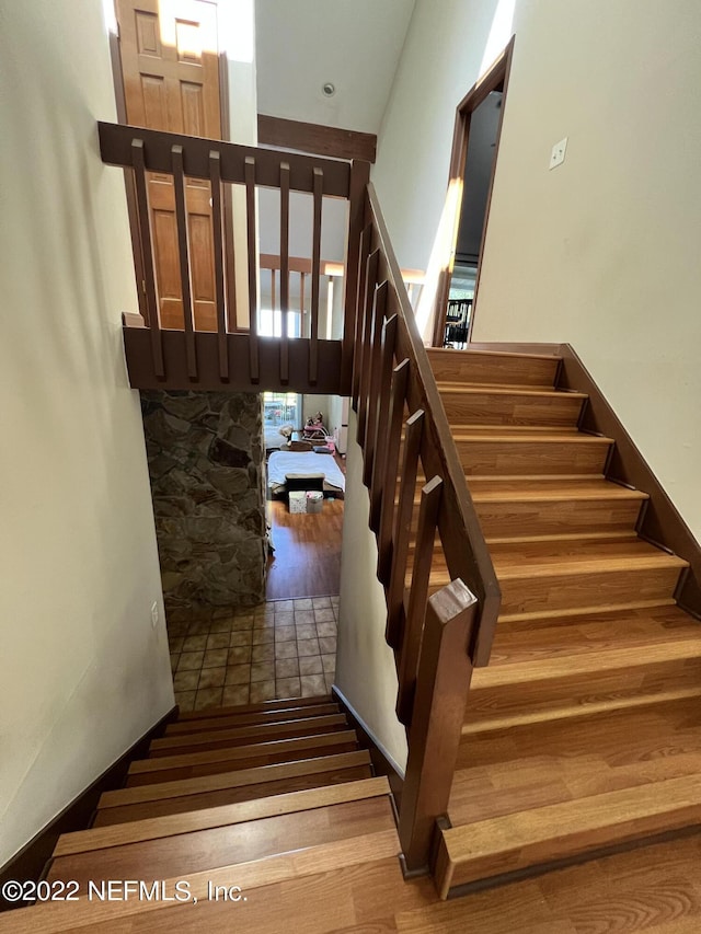 staircase with a high ceiling and hardwood / wood-style flooring