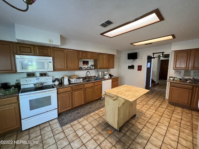 kitchen with a textured ceiling, wood counters, white appliances, and sink