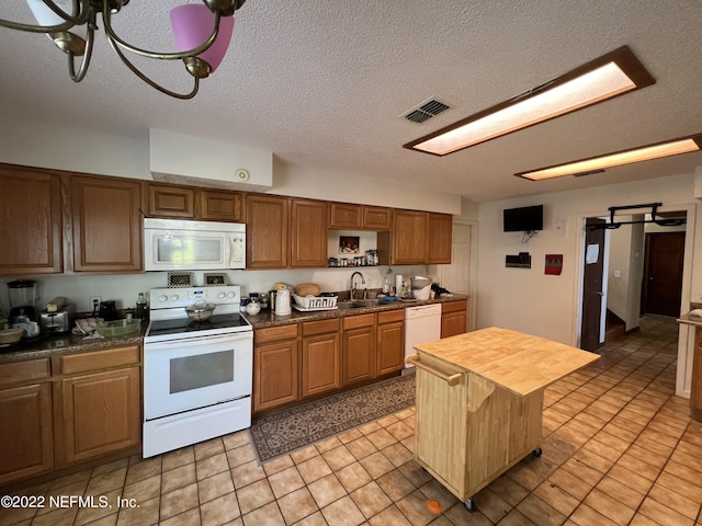 kitchen with wood counters, white appliances, sink, a textured ceiling, and a kitchen island