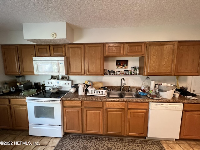 kitchen with a textured ceiling, light wood-type flooring, white appliances, and sink