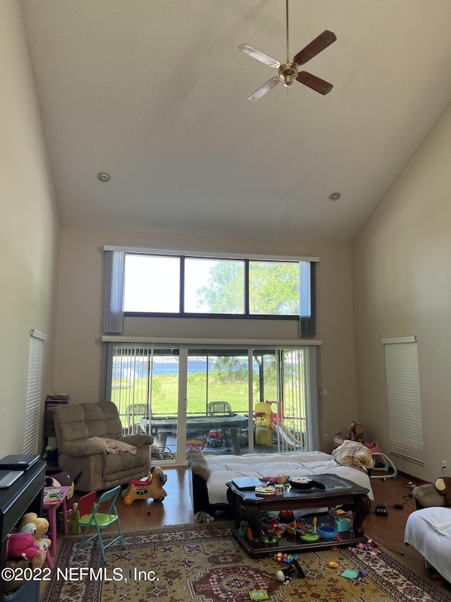 living room with hardwood / wood-style floors, a healthy amount of sunlight, and high vaulted ceiling