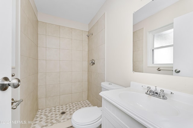 bathroom with tiled shower, vanity, and toilet