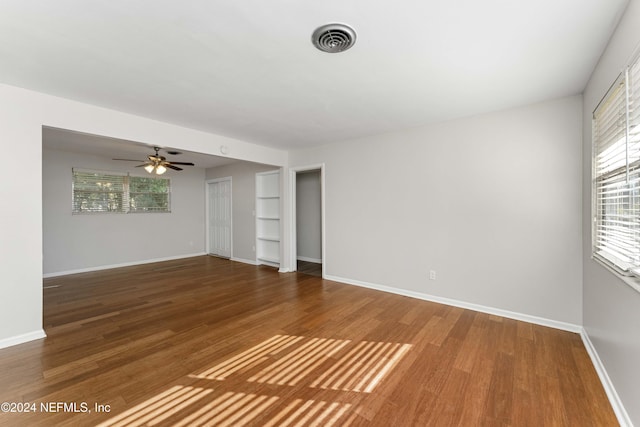 spare room featuring dark hardwood / wood-style floors, built in features, and ceiling fan