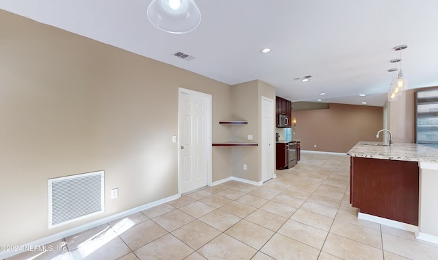 kitchen featuring light stone countertops, dark brown cabinetry, stainless steel appliances, sink, and light tile patterned floors