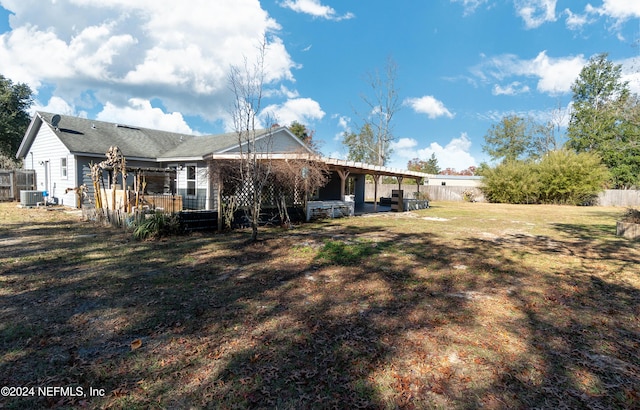 back of property with a lawn and central AC