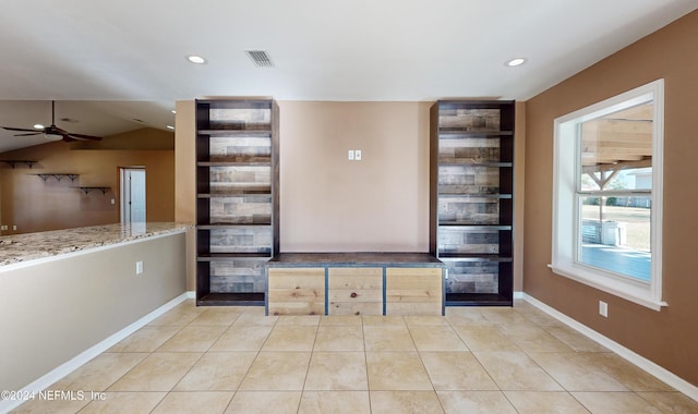 unfurnished living room with ceiling fan, light tile patterned floors, and vaulted ceiling