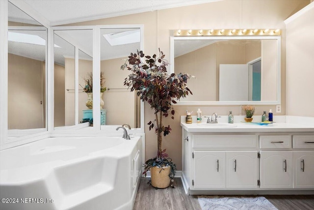 bathroom with hardwood / wood-style floors, vanity, ornamental molding, and lofted ceiling